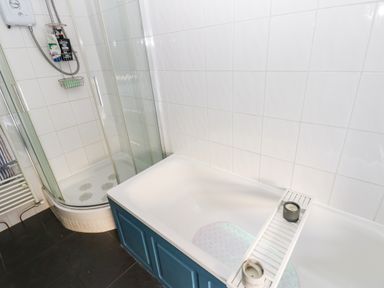 A bathroom with a shower enclosure and a bathtub with candles at Rose Hip Cottage in Bellingham