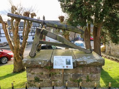 An outdoor historical display of a wooden mounted cannon on a stone platform with a sign in front at Rose Hip Cottage in Bellingham