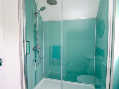 A shower area with a glass door and silver shower fixtures in a bathroom at Sea Rose in Aberporth