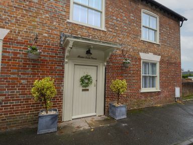 Exterior view of a brick house with a cream door and two windows at Manor Farm House in Bere Regis