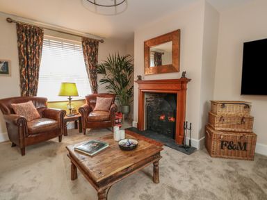 A living room with two leather chairs a wooden coffee table and a fireplace at Manor Farm House in Bere Regis