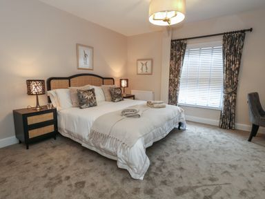 A bedroom with a double bed bedside tables lamps and a window with curtains at Manor Farm House in Bere Regis