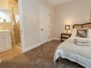 A bedroom with a bed side table lamp rolled towels a door and an adjoining bathroom at Manor Farm House in Bere Regis
