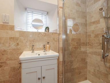 A bathroom with a sink cabinet under a window and a shower area with tiled walls at Manor Farm House in Bere Regis