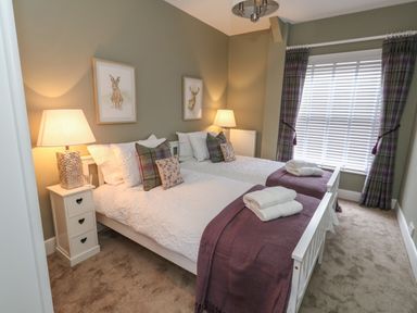 A bedroom with two single beds side by side bedside tables with lamps and a window with blinds and curtains at Manor Farm House Bere Regis