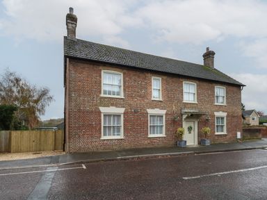 A brick house with six windows a white door and two chimneys on a street at Manor Farm House in Bere Regis