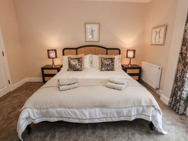 A bedroom with a double bed two bedside tables with lamps and folded towels on the bed at Manor Farm House in Bere Regis