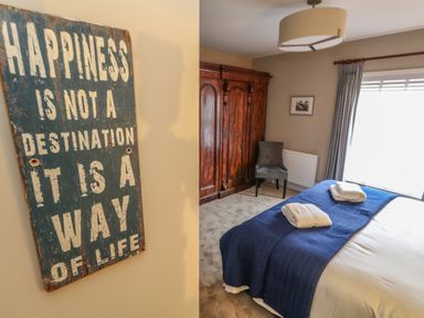 A bedroom with a bed covered with blue bedding and folded towels next to a wooden wardrobe and a chair at Manor Farm House Bere Regis