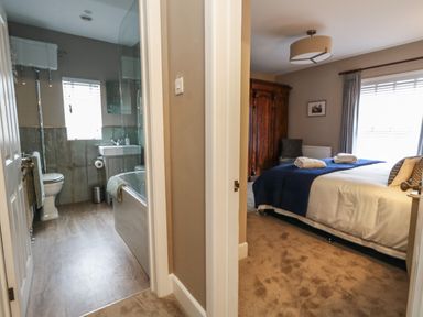 A bathroom with a bathtub and toilet next to a bedroom with a bed and wardrobe at Manor Farm House in Bere Regis