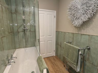 A bathroom with a bathtub shower towel rail and a white door at Manor Farm House in Bere Regis