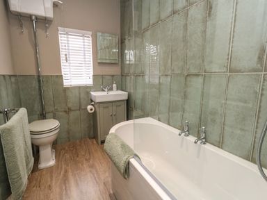 A bathroom with a bathtub sink toilet and window at Manor Farm House in Bere Regis