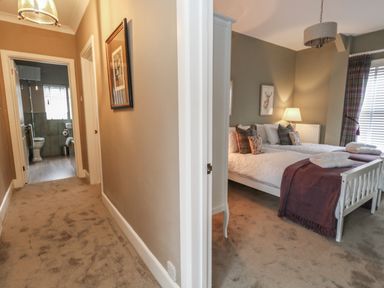 A hallway leading to a bathroom and a bedroom with two single beds with pillows and throws at Manor Farm House in Bere Regis