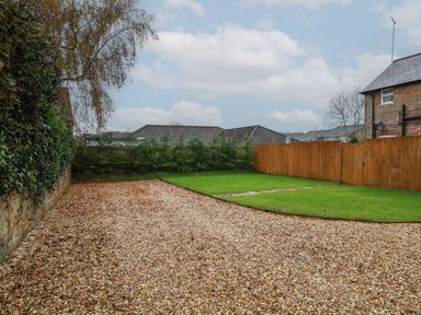 A garden with a gravel driveway a grass lawn and wooden fence at Manor Farm House in Bere Regis