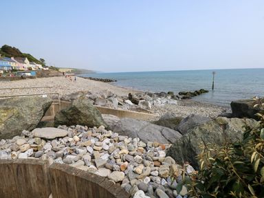 A rocky shoreline with houses in the background and the sea at Folly Cottage in Llanteg near Saundersfoot