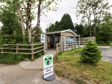 An outdoor small milk and milkshake shop with wooden fencing and trees at Folly Cottage in Llanteg near Saundersfoot