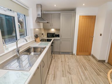 A kitchen with a sink stove microwave and wooden doors at Folly Cottage in Llanteg near Saundersfoot