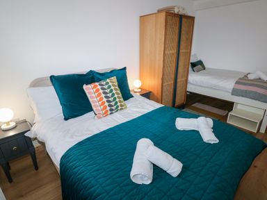 A bedroom with two beds bedside tables lamps and a wardrobe at Folly Cottage in Llanteg near Saundersfoot