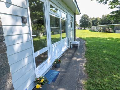Exterior view of a building with a bench flower pots and a grassy lawn at 61 Norton Park in Dartmouth