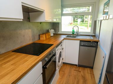 A kitchen with a wooden countertop a sink a washing machine an oven and a dishwasher at 61 Norton Park in Dartmouth