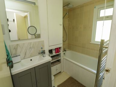 A bathroom with a sink cabinet mirror bathtub shower and window at 61 Norton Park in Dartmouth