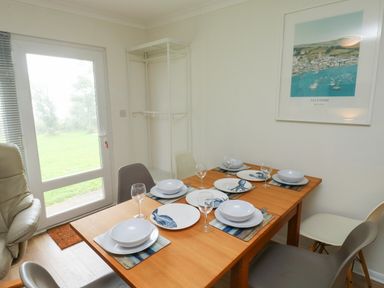 A dining room with a wooden table set with plates and bowls featuring fish and octopus designs and wine glasses at 61 Norton Park in Dartmouth