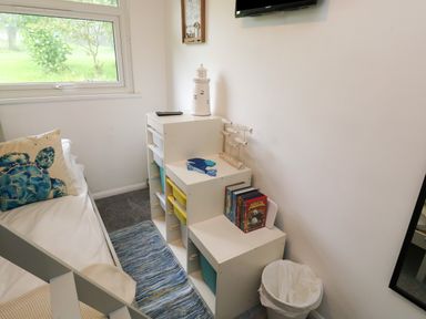 A bedroom corner with a bed a pillow with a turtle print a white storage unit with bins and books and a trash can at 61 Norton Park in Dartmouth