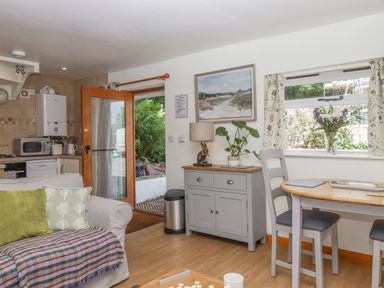 A kitchen and dining area with a sofa pillow and blanket next to a door and window at Dove Cottage Queens Nympton near South Molton