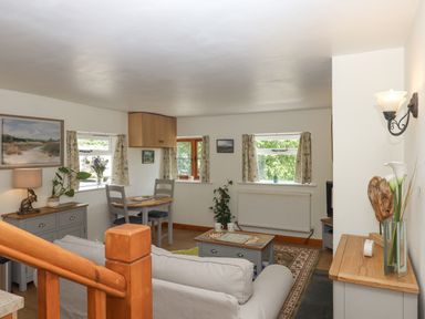 A living room with a sofa coffee table dining table and chairs and plants at Dove Cottage Queens Nympton near South Molton