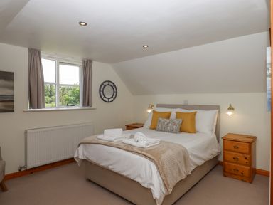 A bedroom with a double bed bedside tables and a window at Dove Cottage in Queens Nympton near South Molton