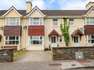 A row of connected houses with bay windows and driveways at 23 Cois Caol in Skibbereen County Cork