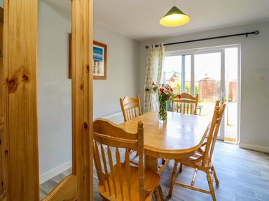A dining area with wooden table and chairs flowers on table and glass door leading to garden at 23 Cois Caol in Skibbereen County Cork