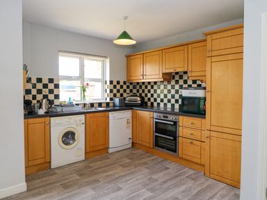A kitchen with wooden cabinets appliances and checkered tile backsplash at 23 Cois Caol in Skibbereen County Cork