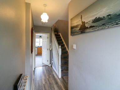A hallway with stairs on the right side and an open door leading to a kitchen at 23 Cois Caol in Skibbereen County Cork