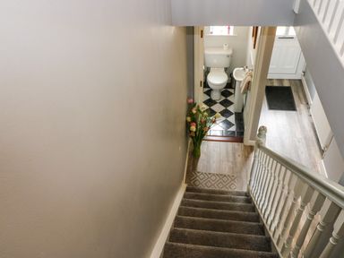 A staircase leading down to a hallway with a vase of flowers and a small bathroom at 23 Cois Caol Skibbereen County Cork