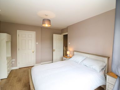 A bedroom with a double bed bedside tables a lamp a wardrobe and two doors at 23 Cois Caol in Skibbereen County Cork