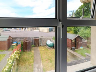 A view through a window showing a backyard with sheds a path and plants at 23 Cois Caol in Skibbereen County Cork