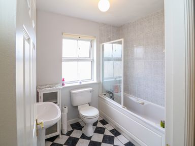 A bathroom with a toilet sink bathtub with shower and a window at 23 Cois Caol in Skibbereen County Cork