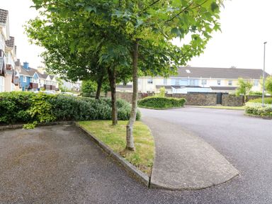 A residential area with trees hedges and parked cars near houses at 23 Cois Caol in Skibbereen County Cork