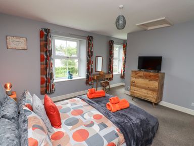 A bedroom with a bed dressed in patterned linens and orange towels on a blanket at Woodcutters Cottage in Park Village near Haltwhistle