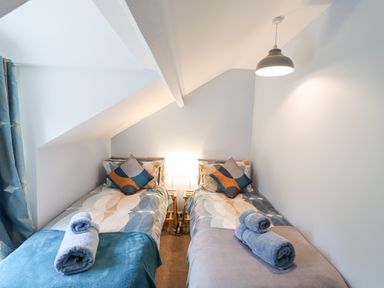 A bedroom with two single beds each with rolled towels and bedside lamps at Woodcutters Cottage Park Village near Haltwhistle
