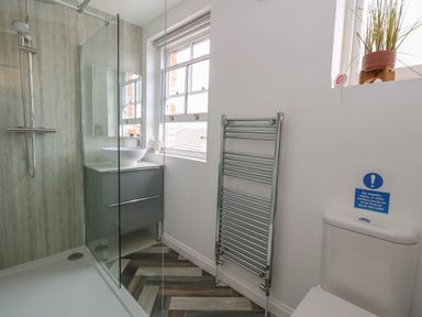 A bathroom with a shower area sink with vanity unit window heated towel rail and toilet at Flat 2 - Studland in Bournemouth