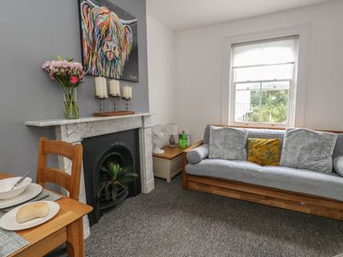 A living room with a wooden sofa with cushions a marble fireplace and a wooden dining table at Flat 4 - Hengistdury in Bournemouth