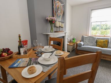 A dining table set with bowls plates glasses and bread near a sofa and fireplace at Flat 4 - Hengistdury in Bournemouth