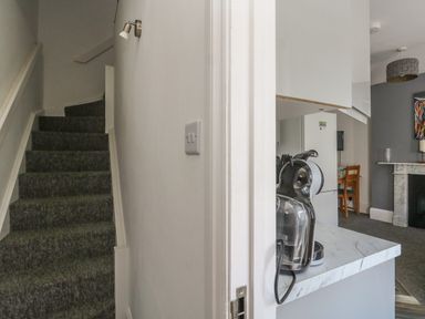 A staircase with grey carpet and a kitchen counter with a coffee machine near a living area at Flat 4 - Hengistdury in Bournemouth
