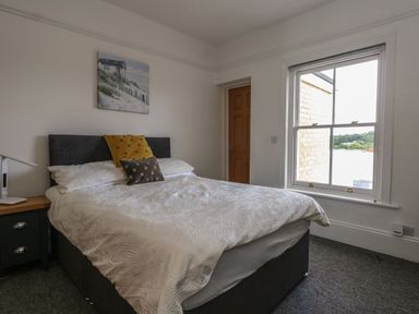 A bedroom with a bed pillows a bedside table and a window at Flat 4 - Hengistdury in Bournemouth