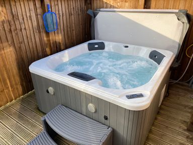A hot tub with water jets on a wooden deck next to a fence and a pool skimmer at Hazel Lodge in Whitby