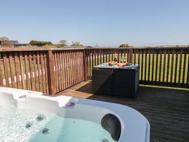 An outdoor area with a hot tub and a table set with food and drinks at Hazel Lodge in Whitby