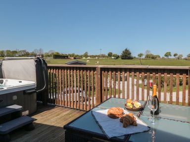 An outdoor deck with a hot tub and a table of food at Hazel Lodge in Whitby