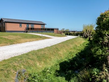 An exterior view of a lodge with a gravel path at Hazel Lodge in Whitby