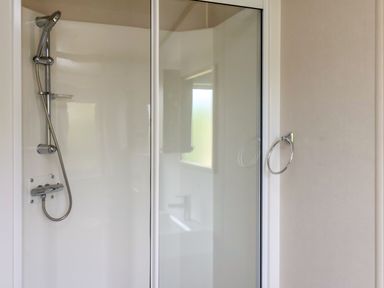 A bathroom shower area with a glass door and a metal showerhead at Willow Lodge in Whitby